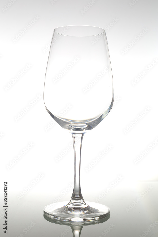 Empty wine glass on glass table. Empty glass on white background. Empty wine glass on glass table. Empty glass on white background.