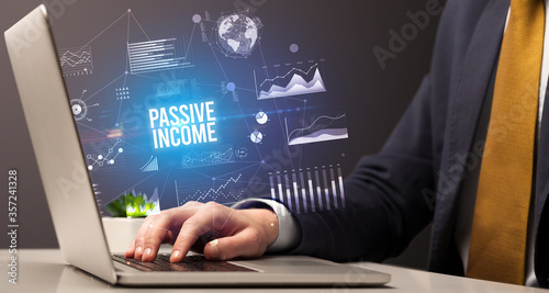 Businessman working on laptop with PASSIVE INCOME inscription, new business concept
