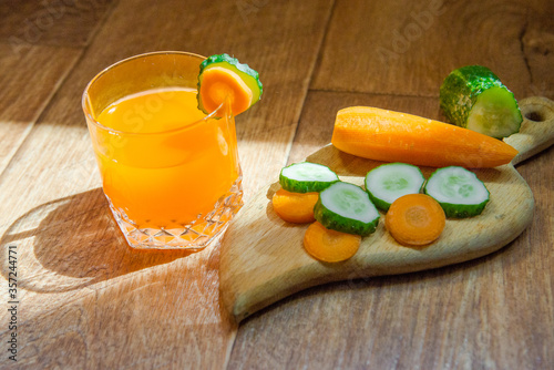 Carrot juice. Healthy food, healthy drink. Cucumbers and carrots. Seasonal vegetables. Orange juice in a glass and next peeled carrots. healthy eating for breakfast. Wood background