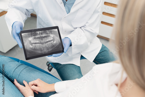 Dentist showing teeth x-ray on tablet screen