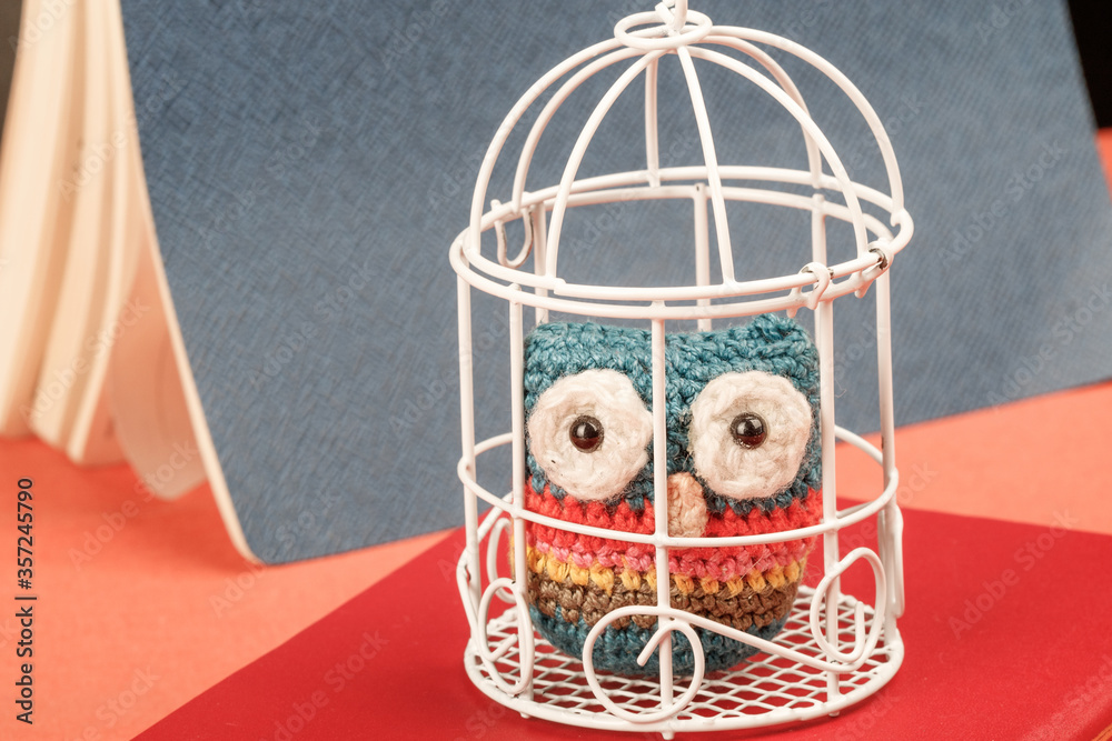 Homemade knitted owl in a metal cage for birds
