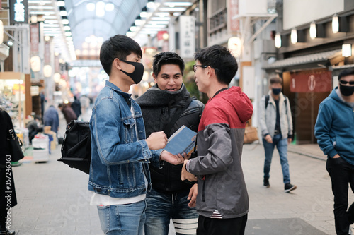 Group of young asian friends talking about the trip to travel on walking street while open the map