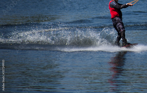 The man does wakeboarding on the water in the summer in a helmet and wetsuit.