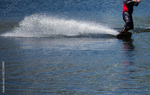 The man does wakeboarding on the water in the summer in a helmet and wetsuit.