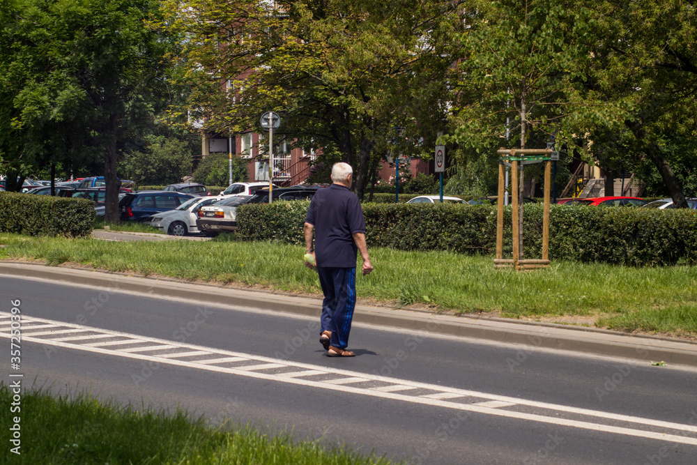 Wroclaw, Poland, June 12, 2020, old man crossing a street in prohibited place, jay walking