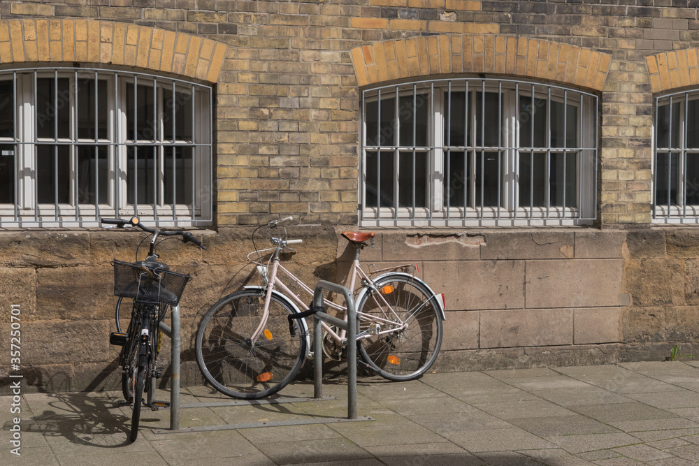 Fahrräder vor einer alten Sichtziegel-Fassade mit vergitterten Rundbogenfenstern