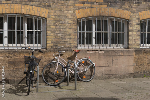 Fahrräder vor einer alten Sichtziegel-Fassade mit vergitterten Rundbogenfenstern © tina7si