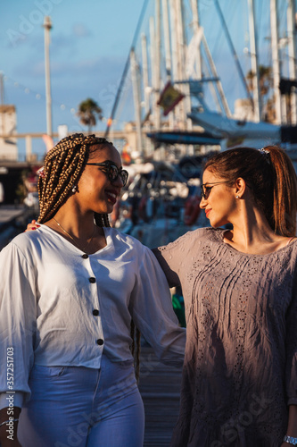 Happy multiracial girlfriends having genuine fun at jetty pier docks. Modern lifestyle with female best friends women