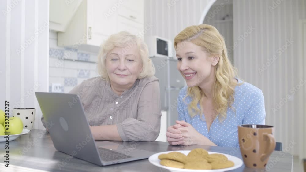 Blond woman and mother talking by online app on laptop, video call with family