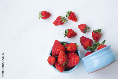 Ripe red strawberries in blue cups on a white background