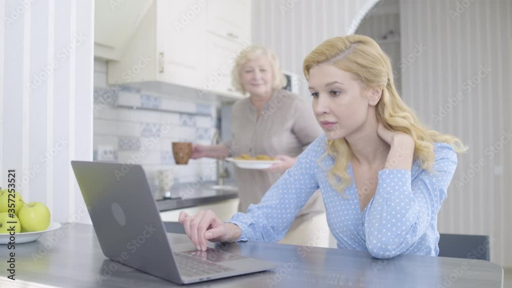 Mother taking care of daughter, working on laptop, offering tea and cookies Mother taking care of daughter, working on laptop, offering tea and cookies