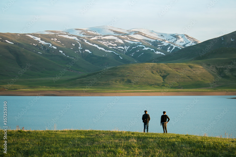 Two standing on the shore of blue lakes and mountains
