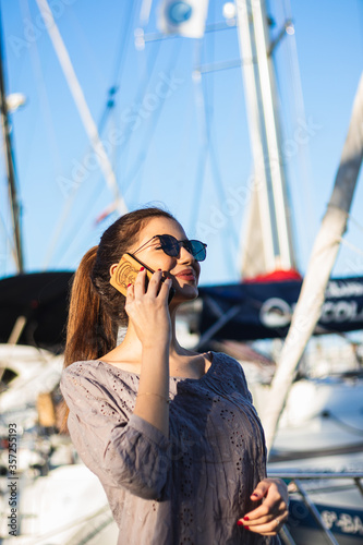 Portrait of a young brunette woman calling with smart phone while enjoying good day outdoors