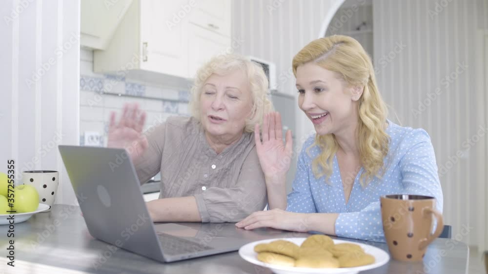 Smiling women communicating by video call, talking to father by online app Smiling women communicating by video call, talking to father by online app