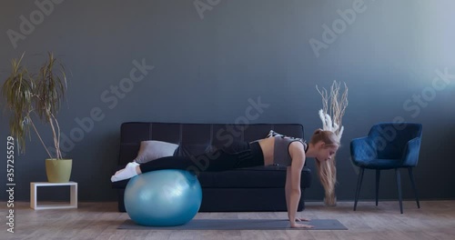 Motivated woman practicing fitball pike push-ups at home