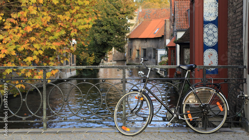 A bicycle on the bridge over the canal with colorful autumn tree, Bruges, Belgium.