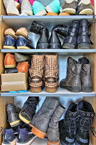 Variety of different women and men shoes packed into a wardrobe.