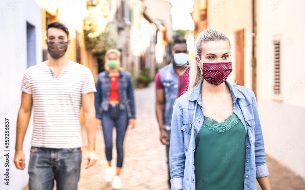Multiracial friends walking with face mask after lockdown reopening - New normal friendship concept with guys and girls spending time together on city streets - Warm filter with focus on right woman