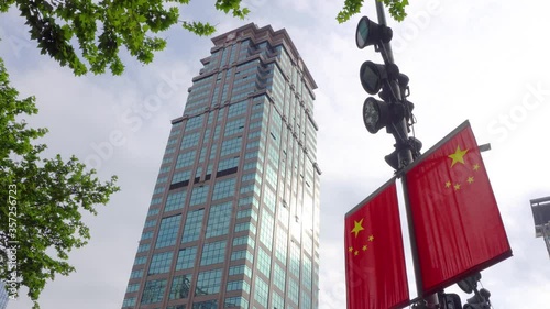 Establishing shot of skyscraper office building in China. Communist China flag with business tower external facade. Offices doing capitalist work. photo