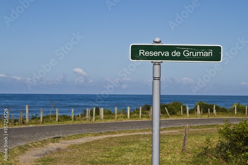 Green signboard with writing "Reserva de Grumari" on the highway next to the sea