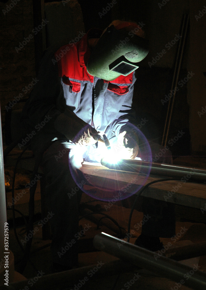 Profesional welder in protective uniform and mask welding metal Profesional welder in protective uniform and mask welding metal