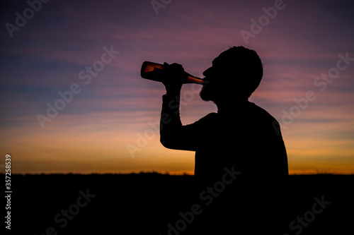 man drinking beer in sunset