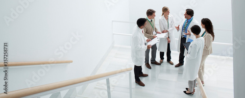 Foto Business people and doctors meeting on landing of stairs