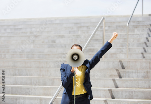 Slika na platnu Businesswoman using megaphone on urban steps