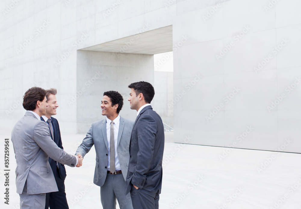 Smiling businessmen shaking hands outside cultural center