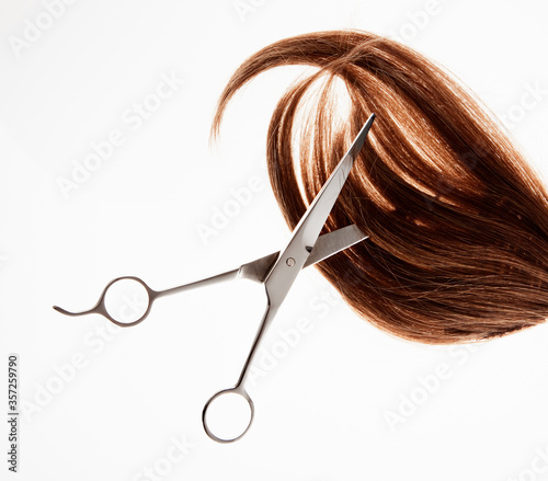 Scissors cutting through brunette hair 