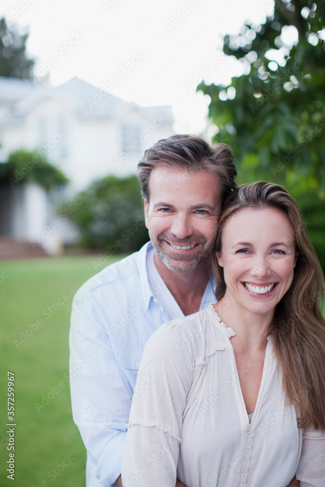 Portrait of smiling couple in yard with house in background Portrait of smiling couple in yard with house in background
