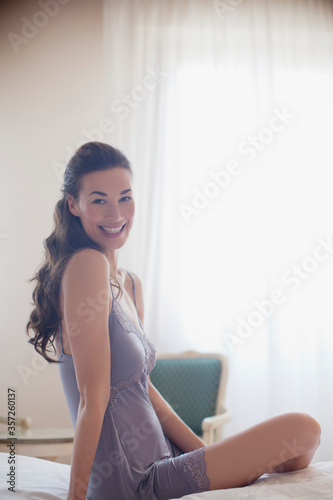 Portrait of smiling woman in nightgown on bed