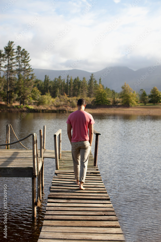 Man walking along dock over lake