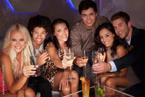 Portrait of smiling friends toasting cocktails in nightclub
