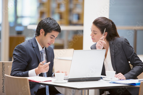 Businessman and businesswoman reviewing paperwork at cafe