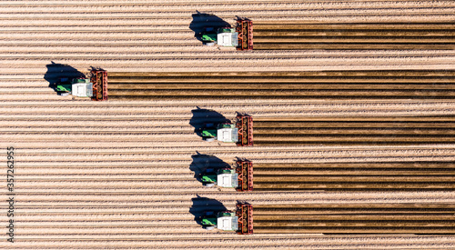 Germany, Hesse, Bergstarsse, Aerial view of tractors plowing brown field in spring