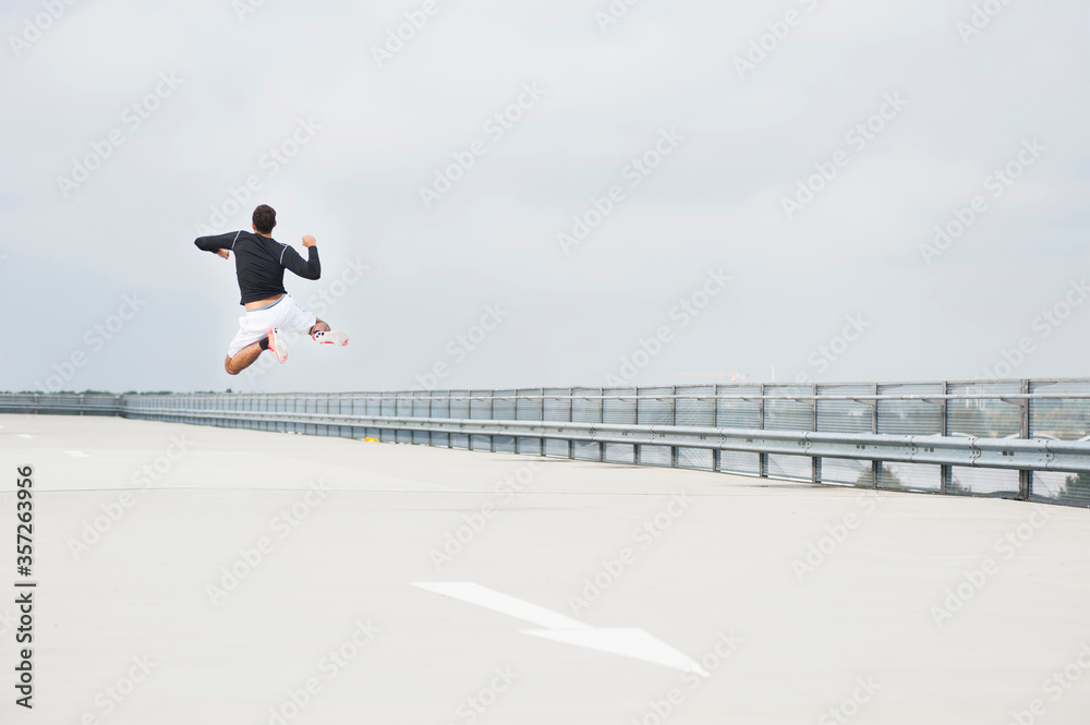 Young man jumping on a parking deck Young man jumping on a parking deck