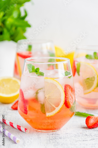Cold summer drink - strawberry lemonade with mint and ice cubes in glass. Vertical, copy space.