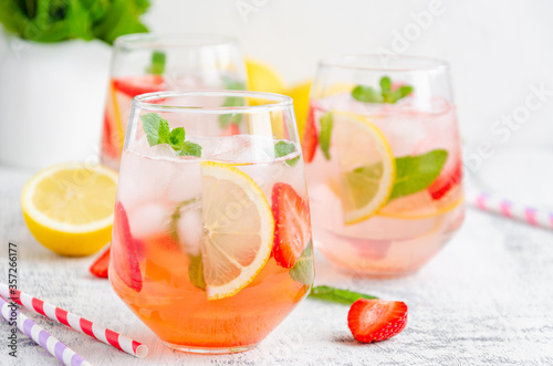 Cold summer drink - strawberry lemonade with mint and ice cubes in glass. Horizontal, copy space.