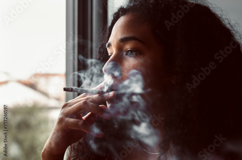 Portrait of young woman smoking a cigarette at the window photo