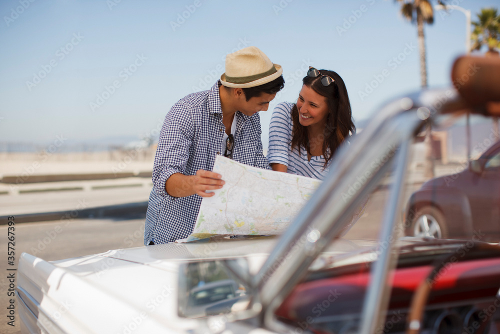 Couple reading road map on convertible