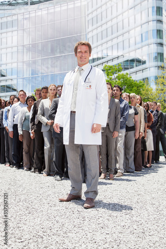 Portrait of smiling doctor with business people in background