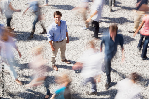 Portrait of smiling businessman surrounded by people rushing by photo