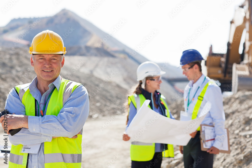 Businessman in hard hat smiling in quarry Businessman in hard hat smiling in quarry