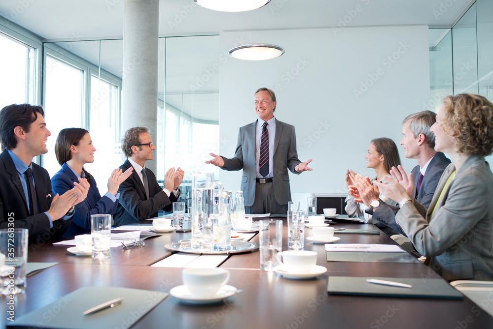 Business people applauding colleague in meeting