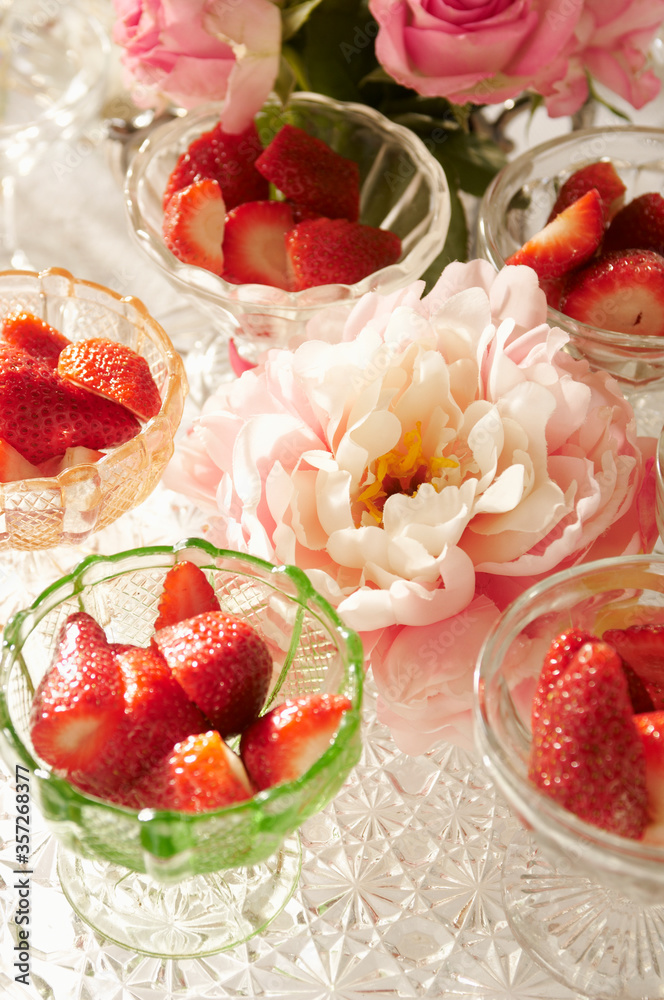 Bowls of strawberries and flowers on table Bowls of strawberries and flowers on table