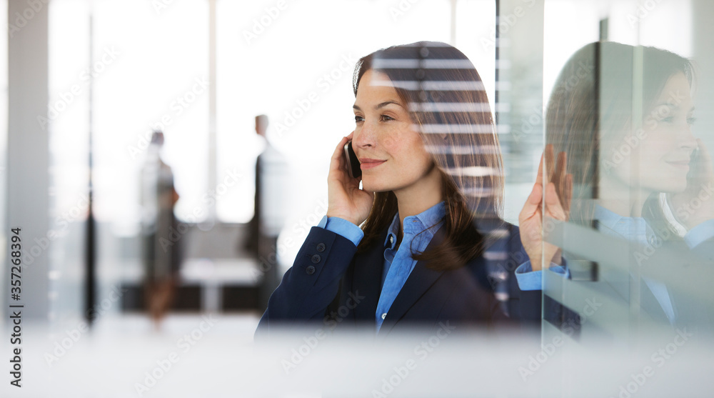 Businesswoman talking on cell phone in office Businesswoman talking on cell phone in office