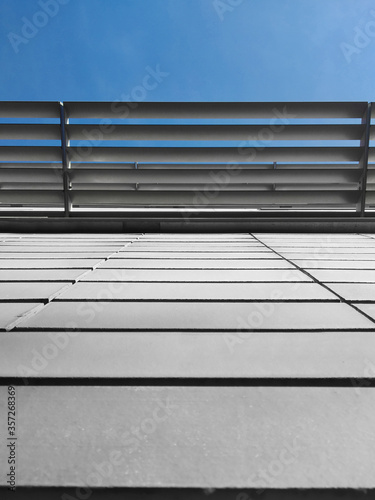 Grey tiles clad building with a metal shade panel on a blue sky