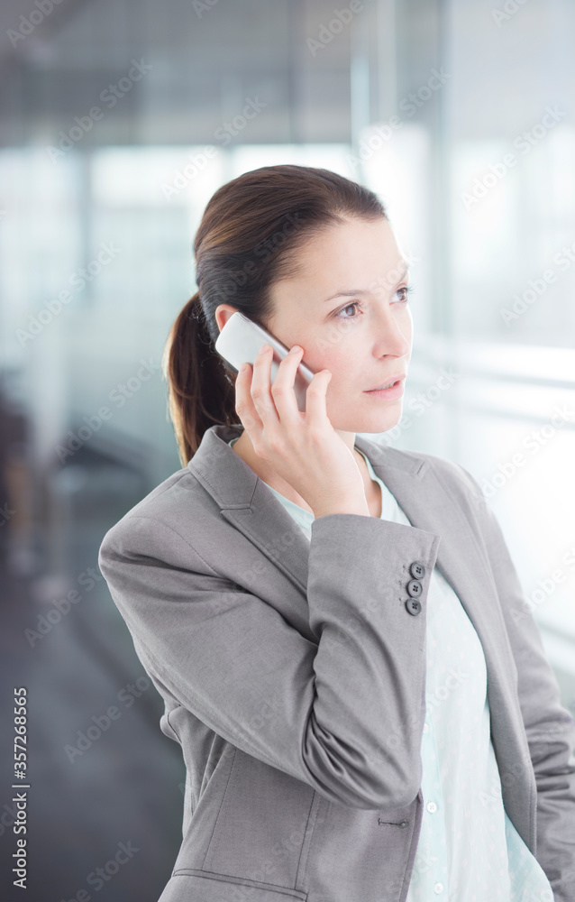 Businesswoman talking on cell phone in office hallway Businesswoman talking on cell phone in office hallway
