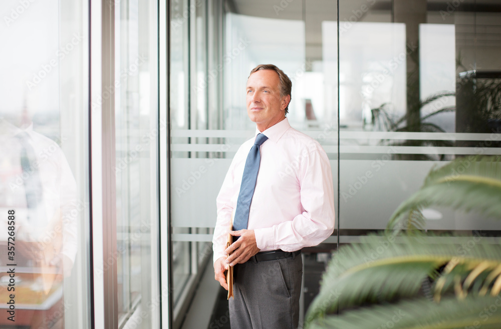 Fototapeta premium Businessman standing at office window
